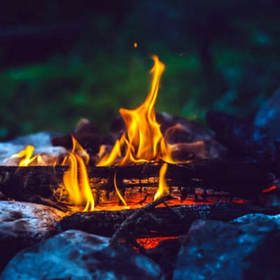 Vivid smoldered firewoods burned in fire close-up. Atmospheric warm background with orange flame of campfire. Unimaginable full frame image of bonfire. Burning logs in beautiful fire. Wonderful flame.